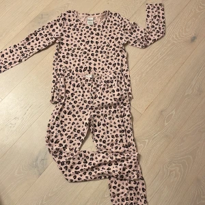 Leopardmönstrad långärmad pyjamas Kappahl - Säljer en rosa långärmad pyjamas från Kappahl med coolt leopardmönster i svart och brunt. Tröjan är i mjuk bomull och har en avslappnad passform, perfekt för dig som gillar att sticka ut lite extra.