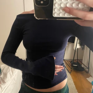 Mörkblå offshoulder topp med utsvängda ärmar - Säljer en mörkblå offshoulder topp med långa, utsvängda ärmar. Sitter tight och har en stilren, minimalistisk look. Perfekt för dig som gillar en enkel men snygg stil. Materialet känns mjukt och stretchigt.