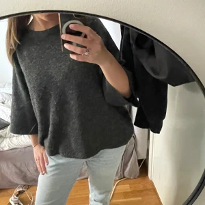 Mörkgrå stickad tröja från 157 - Mysig mörkgrå stickad tröja från 157 med breda trekvartsärmar och avslappnad passform. Perfekt för lager-på-lager och chill dagar. Enkel design som funkar till allt och är superbekväm.