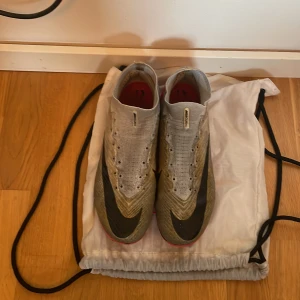 Nike Zoom fotbollsskor vit/röd Elite - Säljer ett par Nike Zoom elite fotbollsskor med stickad ovandel i vitt och röda detaljer. Skorna har svart swoosh, snörning och en strumpliknande krage för extra stöd. Sulan är röd och vit med Zoom-teknologi och mönstrad för bra grepp på planen. Har inte originella snören men kan skicka med ett par vanlig vita