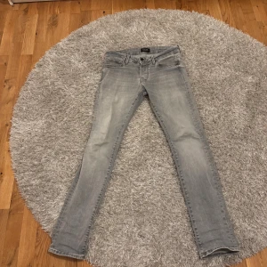 Slim Glenn ljusgrå jeans från Jack & Jones - Säljer ett par Slim Glenn jeans från Jack & Jones i ljusgrå tvätt. Modellen har smal passform, klassisk femficksdesign och dragkedja. Jeansen är tillverkade i stretchig denim för extra komfort och har snygga detaljer på bakfickorna.
