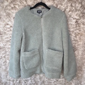 Ljusgrön teddyjacka med dragkedja - Mysig ljusgrön teddyjacka från Bubbleroom med två stora fickor framtill och dragkedja. 