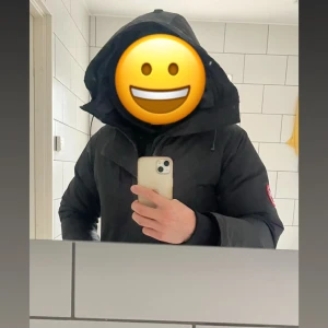 Canada Goose vinterjacka - Säljer en svart dunjacka från Canada Goose med stor huva och klassisk logga på ärmen. Jackan har dragkedja framtill, snörning vid huvan och en clean, stilren look. Perfekt för kalla dagar och har en normal passform.