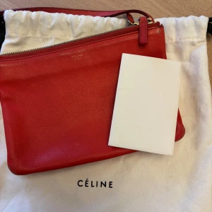 CÉLINE Small Trio Bag - CÉLINE Small Trio Crossbody Bag i rött skinn med guldfärgade beslag. 22x15x4 cm. 