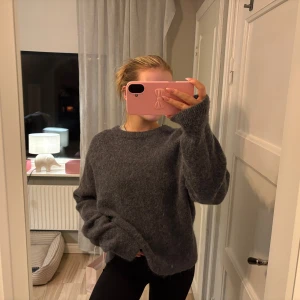 Mörkgrå stickad tröja från H&M - Mysig mörkgrå stickad tröja från H&M i ull- och alpackablandning. Tröjan har en loose fit med rund halsringning och långa ärmar. Perfekt för kyliga dagar och enkel att styla med jeans eller kjol.