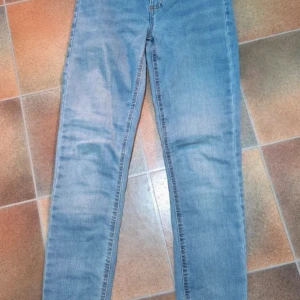 Cubus Jane Skinny Jeans - Ljusblå Stretch, Hög Midja - Strl 34/S - Säljer ett par helt nya och oanvända (NWT-skick, inga lappar men aldrig använda) jeans från Cubus.  Modellen heter Jane Skinny och är en klassisk skinny fit-modell med lite högre midja.  Jeansen har en snygg, ljusblå tvätt och är tillverkade i ett stretchigt material för bästa komfort och passform.  Märke: Cubus Modell: Jane Skinny Storlek: Märkt 34 / Small (S). Färg: Ljusblå tvätt (Medium-Light Wash) Material: 79% Bomull, 20% Polyester, 1% Elastan.