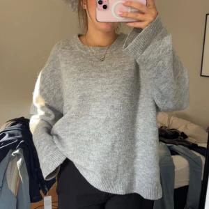 Grå oversized stickad tröja - Mysig grå stickad tröja med oversized passform och rund halsringning. Perfekt för lager-på-lager och chill dagar. Långa ärmar och ribbade muddar ger en avslappnad vibe.