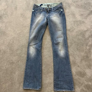 Lågmidjade bootcut jeans  - Snygga lågmidjade blå bootcut jeans från Cross Jeans med slitningar och broderade bakfickor. Perfekta för dig som gillar en avslappnad men trendig look. Säljer då dom tyvärr blivit för små för mig🫶🏼Priset går att diskutera vid snabb affär!