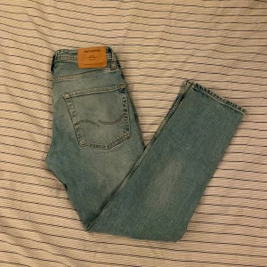 Ljusblå jeans från Jack & Jones - Säljer ett par ljusblå jeans från Jack & Jones med klassisk femficksdesign och snyggt slitna detaljer. Jeansen har normal passform och raka ben, tillverkade i mjukt bomullsjeansmaterial. Perfekta för en avslappnad och stilren look. 27/30