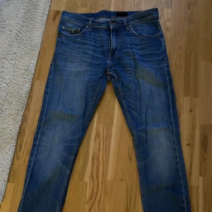 Blå jeans Pistolero 31/32 - Snygga blå jeans från Pistolero i klassisk straight fit med orange kontrastsömmar och fem fickor. Jeansen har normal passform och är tillverkade i slitstarkt denimtyg. Perfekt för dig som gillar en tidlös look med lite faded effekt.