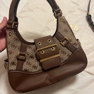 Decor Vintage Bag GUESS - Brun/beige vintage väska från Guess, perfekt till hösten. Helt nyskick, oanvänd. Köpt för 1745 kr, säljer för 975 kr. 