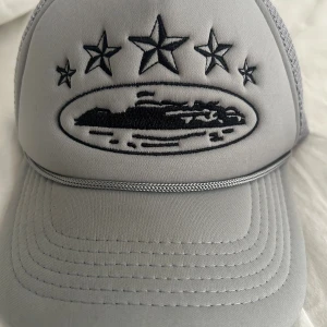 Grå meshkeps från Corteiz - Snygg grå keps från Corteiz med mesh på sidorna och bak, samt justerbar snapback. Samma gäller denna keps först till kvarn 