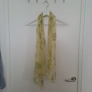 Blommig sidenscarf - Tunn och lätt halsduk i grön blommigt mönster. Scarfen är lång och smal, perfekt att knyta runt halsen eller i håret. 100% silk