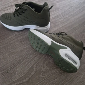 Olivgröna sneakers med vit sula - Snygga olivgröna sneakers med stickad ovandel och vit, chunky sula med luftkudde. Skorna har snörning och rund tå, samt detaljerade mönster i materialet. Perfekta för dig som gillar sportig stil och vill ha bekväma skor till vardags. Platåskor! Lite små i storleken