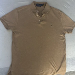 Beige pikétröja Polo Ralph Lauren - Säljer en beige pikétröja från Polo Ralph Lauren i custom slim fit. Klassisk krage, knappar framtill och broderad logga på bröstet. Perfekt för dig som gillar stilren och enkel design. Skön bomullskvalitet och korta ärmar. Har användts ungefär 10 gånger