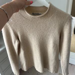 Beige stickad tröja Amina Rubinacci - Snygg beige stickad tröja från Amina Rubinacci med rund hals och långärmad passform. Tröjan har en enkel och clean design, perfekt för dig som gillar stilrena plagg. Mjuk och skön kvalitet som känns lyxig mot huden.