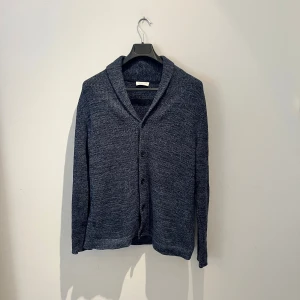 Mörkgrå kofta från Selected Homme - Snygg mörkgrå stickad kofta från Selected Homme i storlek M. Koftan har en bred krage, knappar framtill och långärmade ärmar. Materialet är mjukt och stickat, perfekt för kyliga dagar. Enkel och stilren design som funkar till många olika looks. Hör av er vid fler frågor eller fler bilder