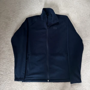 Mörkblå Helly Hansen fleece - Säljer en snygg och skön Helly Hansen fleece tröja i mörkblå färg. Tröjan är endast använd 3 gånger så därför är skicket nästan som ny! Om du har några funderingar är det bara att höra av sig!🛟