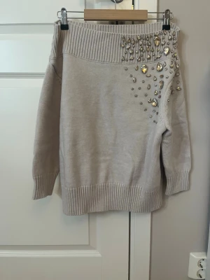 Beige stickad tröja med pärlor  - Supersnygg beige stickad tröja från Anewsta med stora glittriga pärlor och stenar på axeln nytt skick:) 