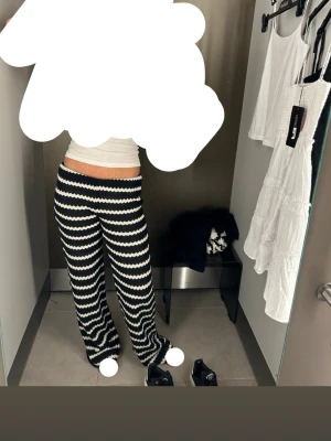 Svarta och vita mjukisbyxor med vågmönster - Säljer ett par riktigt sköna mjukisbyxor med svart och vitt vågmönster. Byxorna har en lös passform och låg midja, perfekta för chill dagar. Tillverkade i mjukt material som känns bekvämt mot huden. Snygga att matcha med en enkel topp eller hoodie.