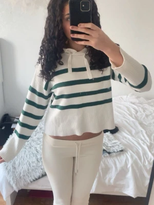 Vit stickad hoodie med gröna ränder - Jättemysig hoodie i vitt med mörkgröna ränder och huva med dragsko. Materialet är verkligen skönt pch supermysigt. Använd väldigt få gånger🩷