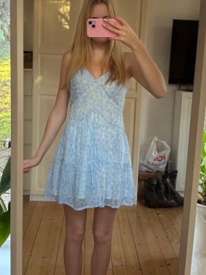 Ljusblå kortklänning med mönster - Supersöt klänning från NA-KD i storlek 34💕 använd två gånger så jättefint skick!!💕