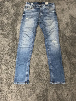 Jack Jones ljusblå slim jeans herr - Säljer ett par ljusblå slim fit jeans från Replay med slitna detaljer och klassisk femficksmodell. Jeansen har normal midja och raka ben, tillverkade i mjukt bomullsjeansmaterial. Perfekta för en avslappnad och trendig look.
