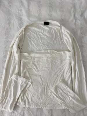 Vit bolerotopp från Gina Tricot - Säljer en vit bolerotopp från Gina Tricot. Toppen är långärmad och har en enkel, stilren design utan mönster eller detaljer. Skrynklig på bild men väldigt fint skick!