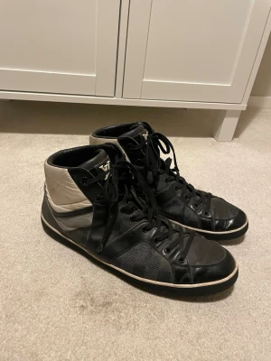 Svarta high top sneakers Louis Vuitton - Säljer LV skor vet dock inte om de är äkta eller inte. De är väl använda och har en del slitage precis som man ser på bilderna. De står ingen storlek i dem men skulle gissa på ungefär 45/46. Priset ej hugget i sten, kom med ett förslag. Som sagt vet jag inte om de är äkta. Hör av dig vid frågor eller om du vill ha fler bilder.😊