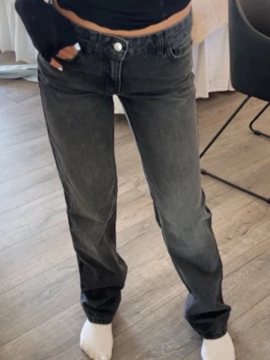 Zara jeanse  - Säljer ett par jeans i svart tvätt med raka ben och normal passform. Jeansen har fem fickor, knappgylf och är tillverkade i kraftig bomullsdenim. Perfekta för en avslappnad och stilren look.