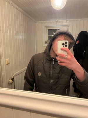 Grå hoodie från Moncler med dragkedja - Snygg grå hoodie från Moncler med quiltad framsida och dragkedja. Hoodien har en klassisk Moncler-logga på bröstet och är perfekt för dig som gillar streetwear. Mjukt innerfoder och praktisk huva gör den både bekväm och stilren. Lappen i tröjan har tyvärr blivit bort riven därför får den som köper dem för detta pris. Annars hade jag velat haft 2000 