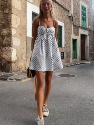 Vit prickig kort sommarklänning💖💖😃🥹 - Söt vit kort klänning med svarta prickar och tunna axelband. Klänningen har en luftig passform och är perfekt för varma dagar. Den har en lätt utställd form och är tillverkad i ett tunt, bekvämt material.