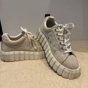 Eytys sneakers i linne - Säljer ett par beige sneakers från eytys, vit platåsula och snörning. Ovandelen är i textil och sulan har en cool, grov design som sticker ut. Perfekta för dig som vill ha något unikt och trendigt till vardagslooken.