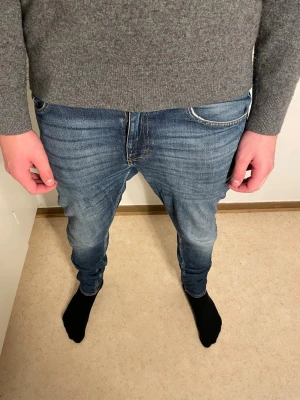 Blå jeans från tiger of sweden - Säljer ett par blå tiger of sweden jeans med slim passform och klassisk femficksdesign. Jeansen har en snygg tvätt med lätt slitning och smal siluett som sitter tajt längs benen. Perfekt för dig som gillar en modern och stilren look.