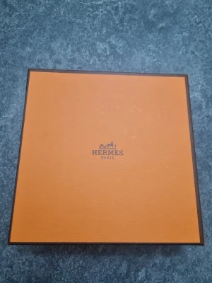 svart/mörkblå läderbälte med H-spänne - Snyggt svart bälte i läder med det ikoniska H-spännet i metall. Kommer med original orange box, dustbag och äkthetskort. Perfekt accessoar för att lyfta din outfit med lyxig känsla och klassisk design.