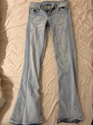 Cheap Monday ljusa bootcut jeans 27/32 - Säljer ett par ljusblå bootcut jeans från Cheap Monday i storlek 27/32. Jeansen har klassisk femficksdesign, slitna detaljer vid benslut och är tillverkade i bomull. Perfekta för dig som gillar retrovibbar och vill ha en avslappnad look.