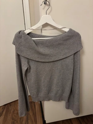 Grå offshoulder stickad tröja  - Säljer en grå stickad tröja från Lager157 storlek S. Tröjan har en bred, ribbad offshoulder-krage och långa ärmar. Perfekt för dig som vill ha en chill men ändå snygg look. Passar till både jeans och kjol.