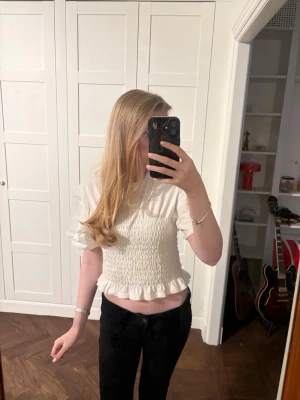 Smockad vit topp, Monki🩷 - Säljer denna supersöta smockade vita toppen ifrån Monki. Den är i jättefint skick och nästan oanvänd. Toppen är i storlek M men sitter mer som en S/Xs eftersom att den är ganska liten i storleken. Hör av er vid frågor eller önskemål om fler bilder osv. 🩷🩷