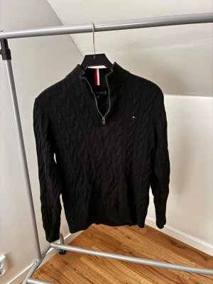 Svart kabelstickad tröja Tommy Hilfiger - Säljer en svart kabelstickad tröja från Tommy Hilfiger med half zip och hög krage. Tröjan har lång ärm och den klassiska lilla loggan på bröstet. Perfekt för dig som gillar stilrena och tidlösa plagg. Pris kan diskuteras vid snabb affär🤝 Passar dig mellan 160-170 cm