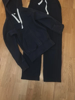 Mörkblå mjukis sett från russemerch - Mörkblått mjukis sett från russemerch. Tröjan är i storlek xs och byxorna i xs long. Bra skick dock väl använda så zip tröjan är lite ”ljusare vid fickorna men syns inte tydligt. Byxorna och tröjan kan köpas separat, 350 för byxorna, 200 för tröjan.  (1200 original pris för båda)