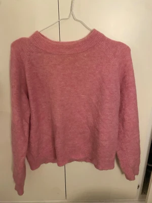 Rosa stickad tröja  - Mysig rosa stickad tröja med rund halsringning och långa ärmar. Tröjan har en avslappnad passform och ribbade muddar vid hals, ärmslut och nederkant. Tröjan är i storlek M men jag skulle säga att den mer är en storlek s/xs