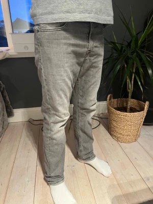Grå straight fit  jeans modell Thad - Snygga grå jeans med straight passform och klassisk femficksdesign. Jeansen har en ljus tvätt och är tillverkade i mjuk bomullsdenim med lite stretch för extra komfort. Perfekta till en avslappnad stil och passar till det mesta.I väldigt bra skick. Passar dig runt 160cm 