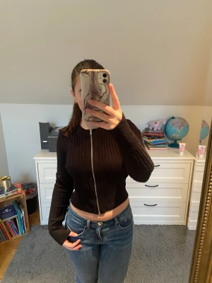 Svart ribbad kofta med dragkedja - Säljer en svart ribbad kofta från H&M med lång ärm och hel dragkedja framtill. Modellen är croppad och sitter tajt, perfekt till jeans eller kjol. Rund hals. Bara använd några gånger så väldigt bra skick. 