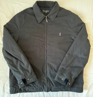 Svart Yves Saint Laurent jacka - Supersnygg YSL jacka i riktigt bra skick. Väldigt varm och skön, så perfekt för höst/vinter :) Har i princip inga defekter förutom att fordret syns lite grann på insidan som går att se i sista bilden. Hör gärna av dig om du har några funderingar!