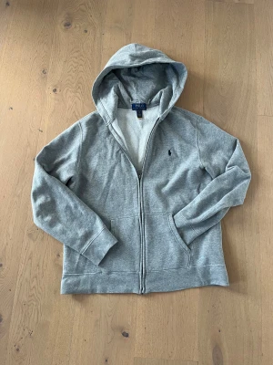 Grå hoodie från Polo Ralph Lauren - Säljer en grå hoodie från Polo Ralph Lauren i storlek xs. (Storleken på lappen är barnstolek) men allmänt snygg: skick 8,5/10 väldigt bra och väldig prisvärd. Nypris 1200kr