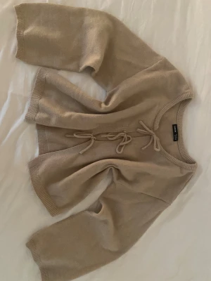 Beige stickad kofta med knyt från SHEIN - Säljer denna superfina kofta från SHEIN då jag själv inte använder den☺️Kontakta mig gärna ifall du vill ha fler bilder eller mått! 
