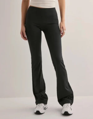 Svarta bootcut träningsbyxor - Snygga svarta bootcut träningsbyxor med hög midja och stretchigt material som sitter skönt. Perfekta för dig som gillar en sportig look och vill ha bekväma byxor med lite utsvängda ben. Passar till sneakers och crop tops.