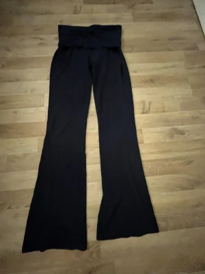 Svarta vida byxor från Gina Tricot XXS - Svarta byxor från Gina Tricot i storlek XXS. De har hög midja med bred linning och vida ben för en chill och trendig look. Perfekta att styla med crop top eller hoodie. Mjukt material som känns skönt mot huden. Yoga pants