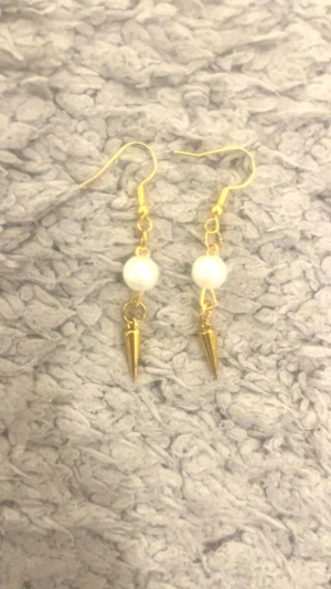 Guldiga örhängen med pärlor och spikes - Snygga örhängen med guldfärgade krokar, vita pärlor och coola spetsiga detaljer i guld. Perfekt för dig som vill ha något unikt och trendigt som sticker ut. Passar till alla tillfällen när du vill addera lite edge till din look.