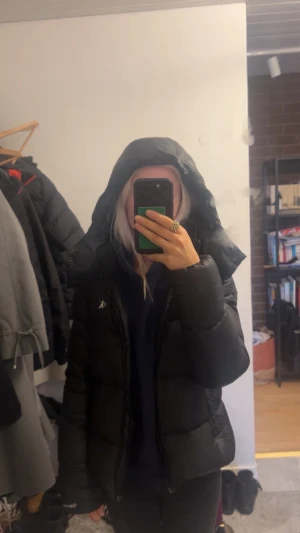 Svart pufferjacka från Calvin Klein - Svart pufferjacka från Calvin Klein med huva och diskret CK-logga på bröstet. Jackan har en rak, normal passform och är quiltad med dragkedja framtill. Perfekt för kalla dagar när du vill hålla stilen enkel och clean. Den är storlek M men skulle även passa någon med storlek S! Skriv om du vill ha fler bilder på jackan💕